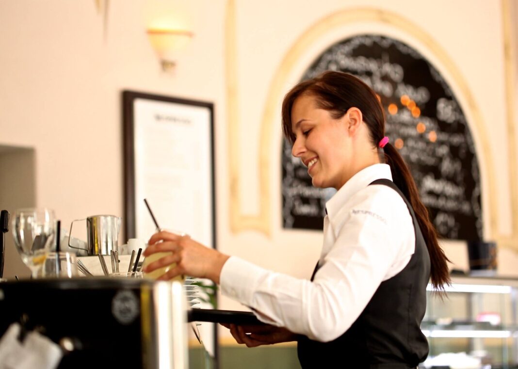 waitress-2376728_1920 Freundliche Kellnerin übergibt ein Getränk an einen Gast in einem Café.