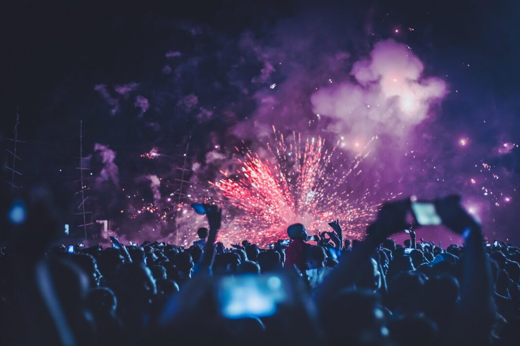 LBV-033 Menschenmenge bei Nacht beobachtet ein farbenfrohes Feuerwerk am Himmel, viele halten Smartphones hoch, um den Moment festzuhalten.