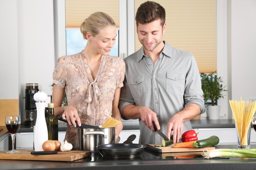 Zwei junge Erwachsene kochen gemeinsam in einer modernen Küche – Symbolbild für gemeinschaftliches Wohnen im Co-Living.